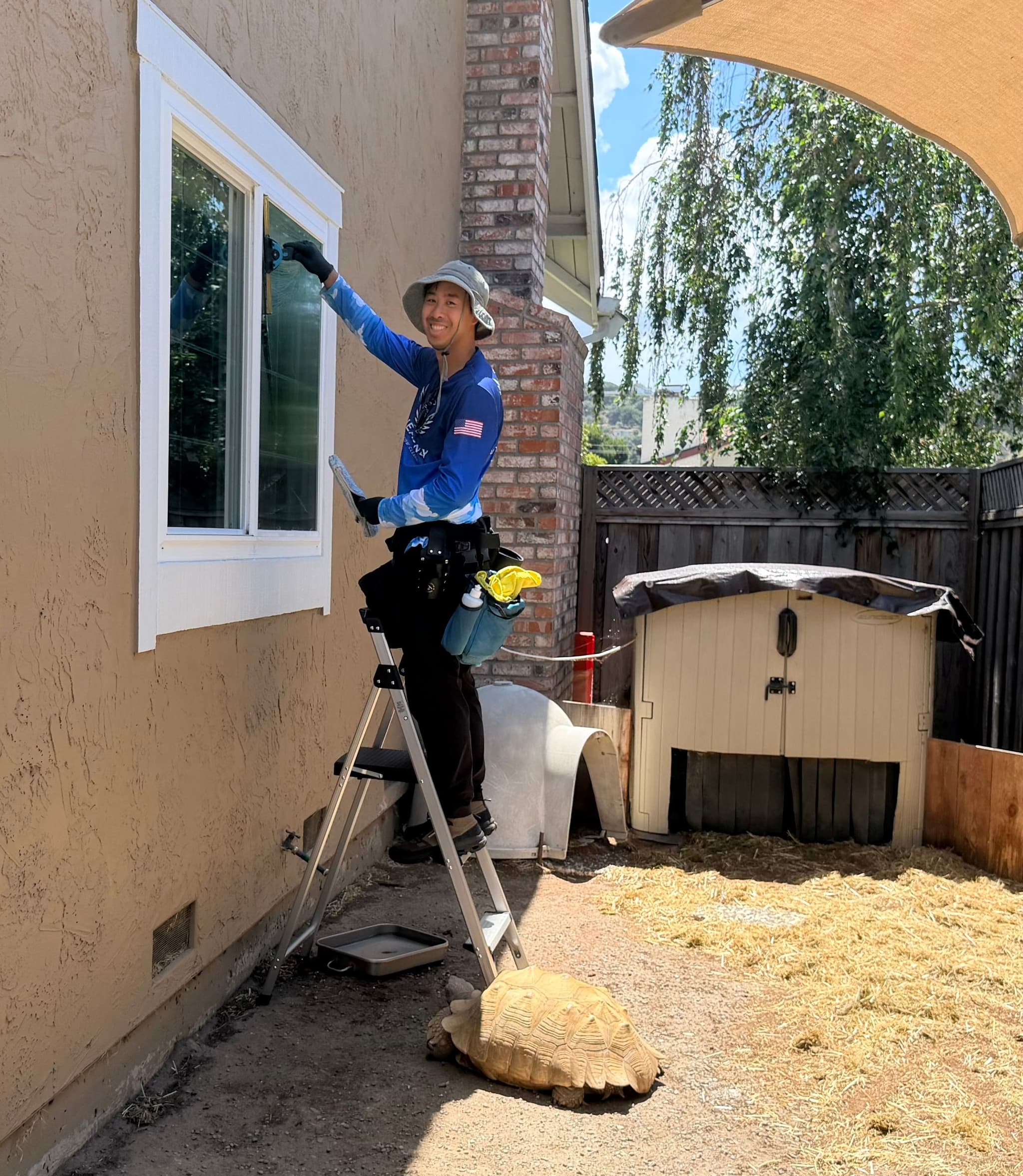 Technician on a ladder working on the exterior of a post war stucco house