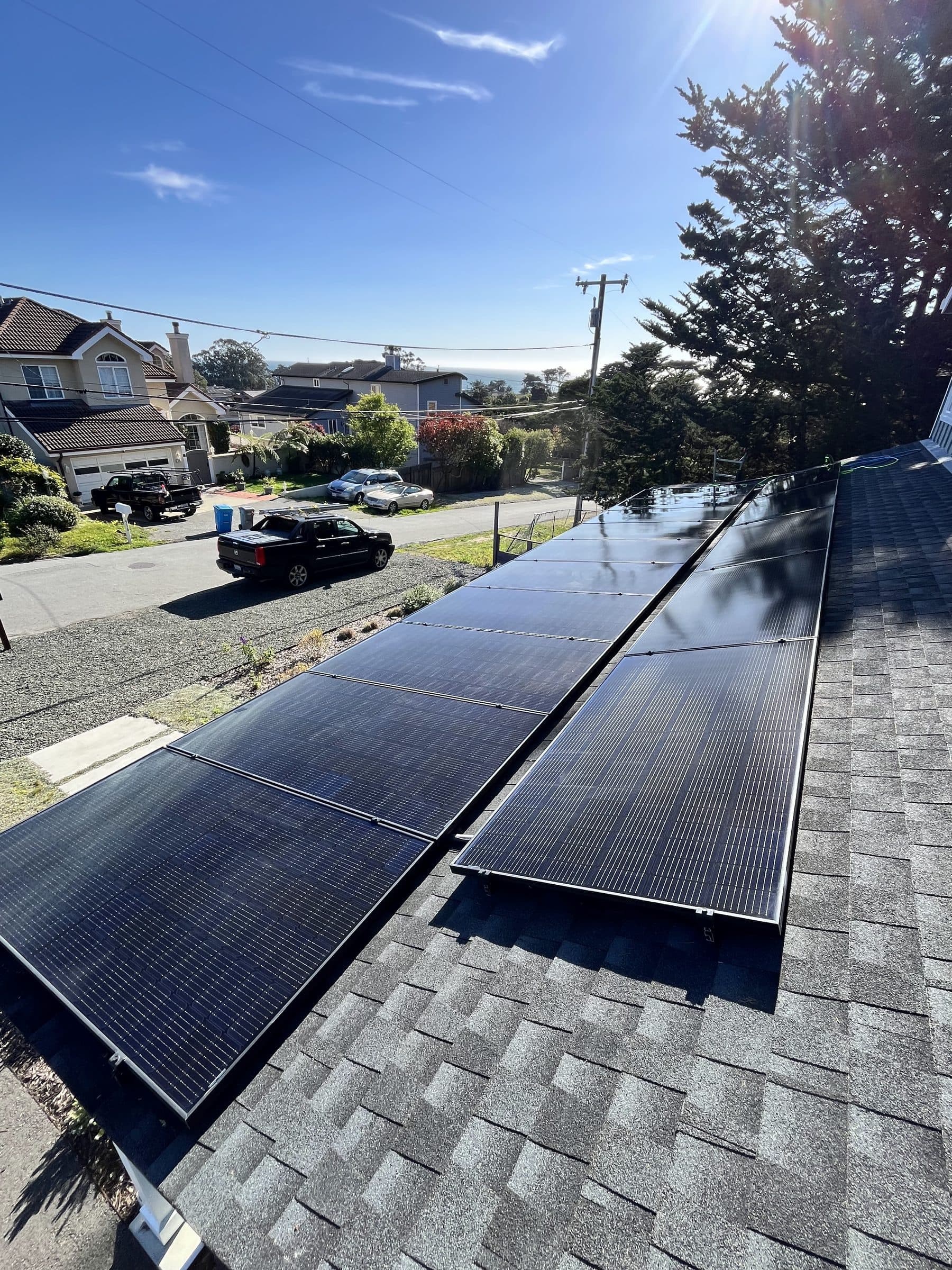 Rooftop solar panels on a hillside home above a residential street